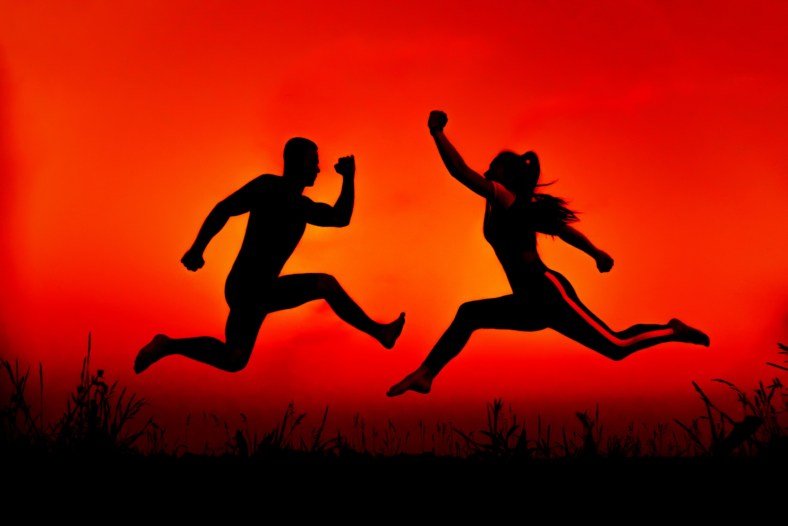 Silhouettes of a sports jumping couple. Concept of gender conflict between a man and a woman